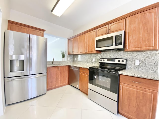 kitchen featuring sink, light tile patterned flooring, stainless steel appliances, and light stone countertops