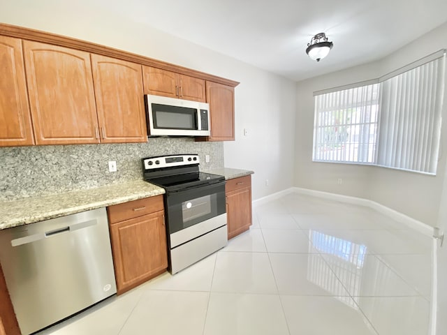 kitchen with light stone counters, light tile patterned floors, decorative backsplash, and appliances with stainless steel finishes