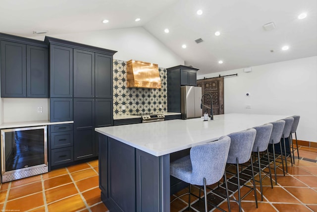 kitchen with wine cooler, a large island, stainless steel appliances, a barn door, and custom range hood