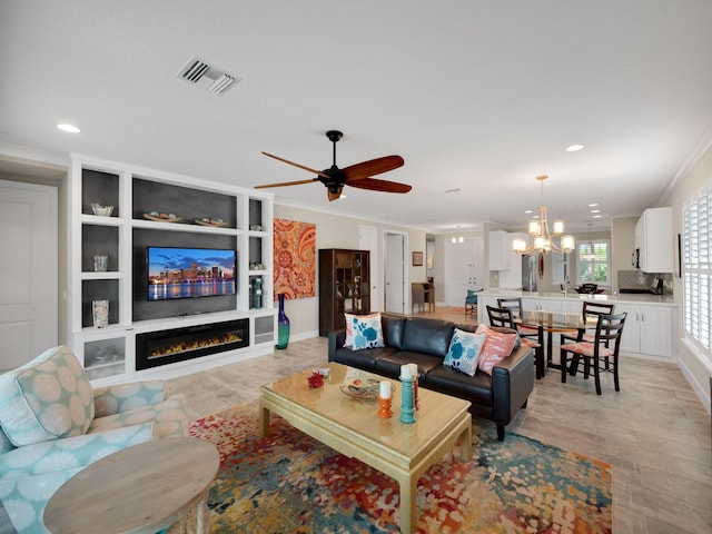 living room featuring crown molding and ceiling fan with notable chandelier