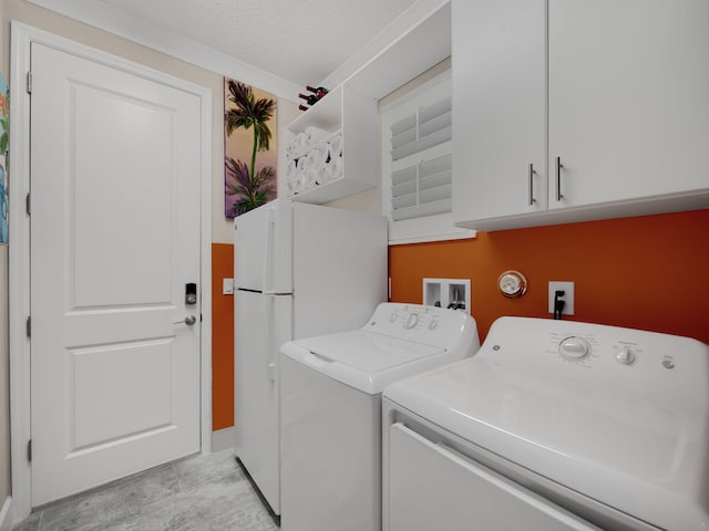 laundry area with cabinets, washer and dryer, and a textured ceiling