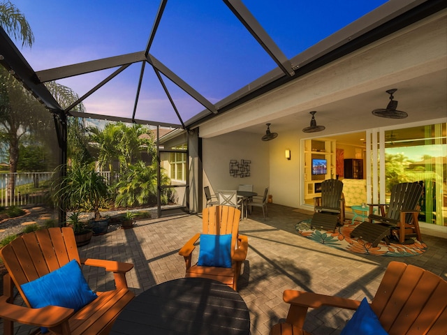 patio terrace at dusk featuring a lanai and ceiling fan