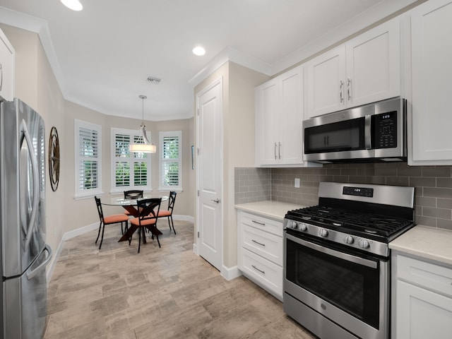 kitchen with stainless steel appliances, ornamental molding, hanging light fixtures, and white cabinets