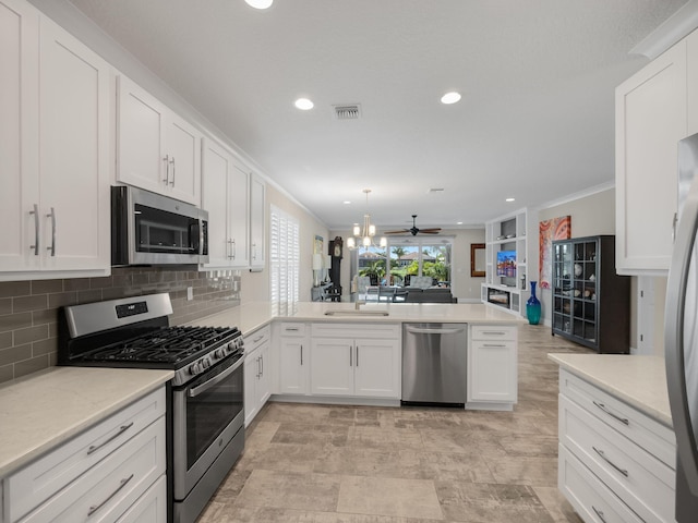 kitchen with sink, crown molding, kitchen peninsula, stainless steel appliances, and white cabinets