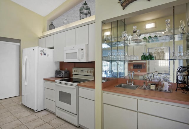 kitchen with sink, light tile patterned floors, white cabinets, and white appliances