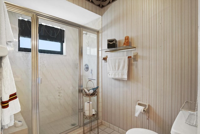 bathroom featuring tile patterned flooring, a shower with shower door, and toilet