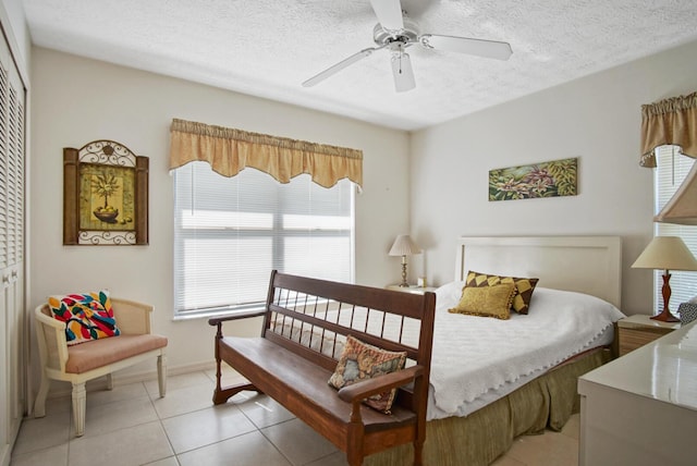 bedroom with light tile patterned floors, a textured ceiling, ceiling fan, and a closet