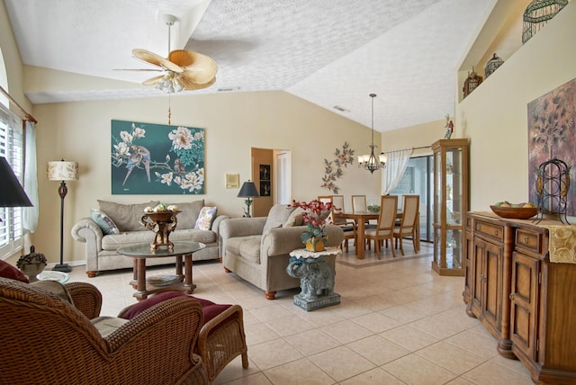 tiled living room with lofted ceiling, ceiling fan with notable chandelier, and a textured ceiling