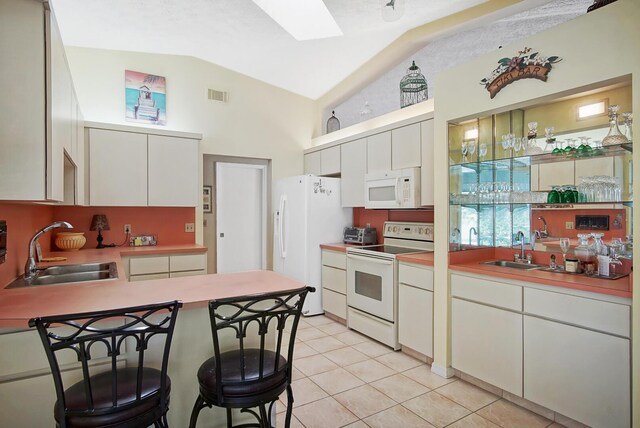 kitchen with white cabinetry, lofted ceiling, sink, and white appliances