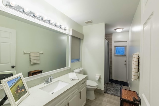 bathroom with a shower with shower curtain, vanity, toilet, and hardwood / wood-style floors