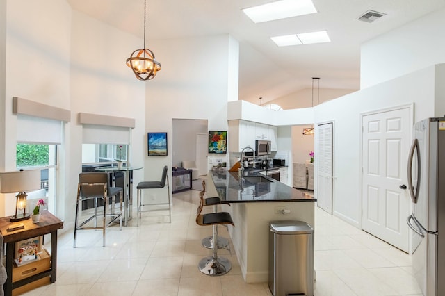 kitchen with appliances with stainless steel finishes, lofted ceiling, a kitchen bar, hanging light fixtures, and kitchen peninsula