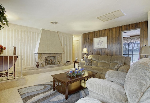 living room featuring carpet floors, a fireplace, and wood walls