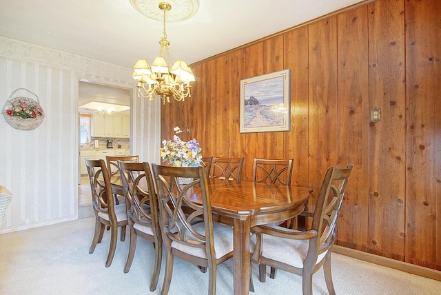 dining room featuring an inviting chandelier, light carpet, and wooden walls