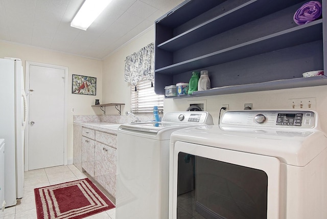 laundry area featuring light tile patterned flooring, sink, cabinets, washing machine and clothes dryer, and crown molding