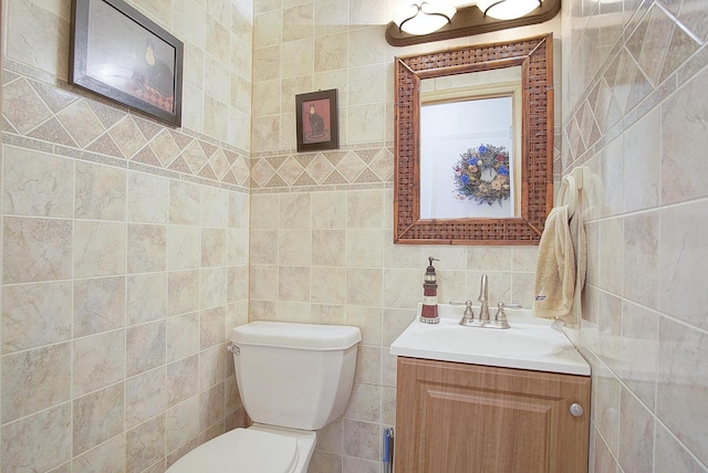 bathroom featuring vanity, toilet, and tile walls