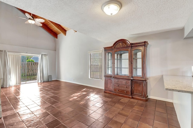 spare room with ceiling fan, beam ceiling, dark tile patterned flooring, and a textured ceiling