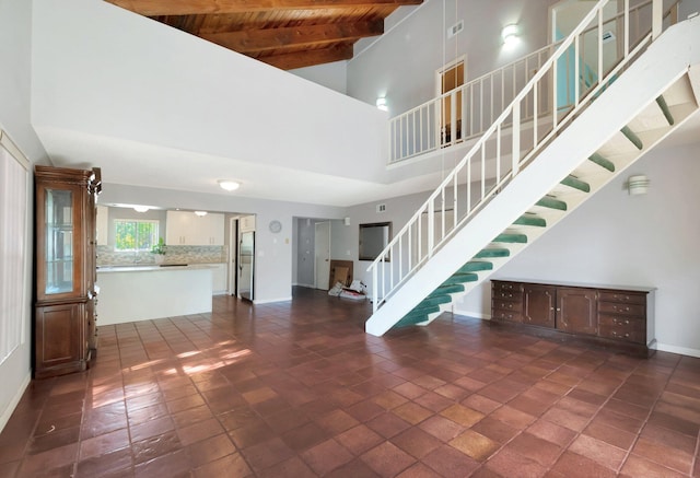 unfurnished living room featuring beam ceiling, wood ceiling, and a high ceiling