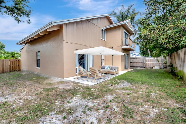 back of property featuring a balcony, a yard, and a patio