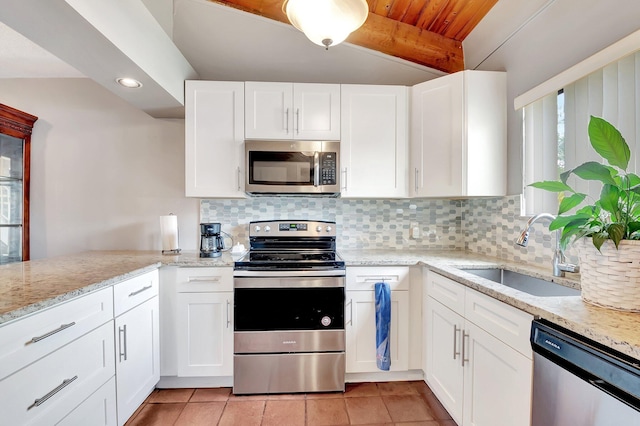 kitchen with sink, appliances with stainless steel finishes, white cabinetry, light stone counters, and tasteful backsplash