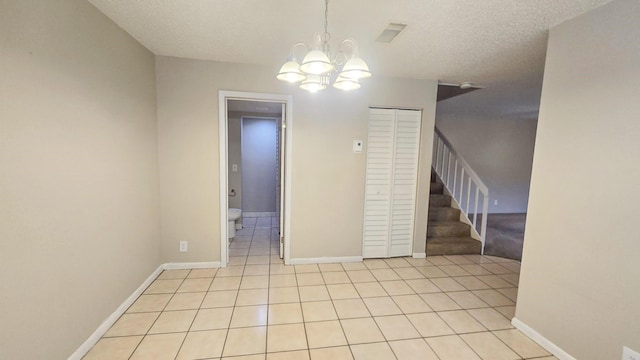 unfurnished room featuring light tile patterned flooring, a chandelier, and a textured ceiling