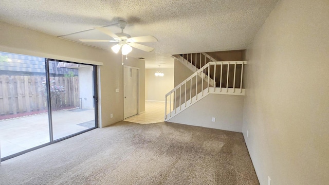 carpeted spare room featuring ceiling fan with notable chandelier and a textured ceiling