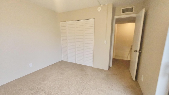 unfurnished bedroom with light carpet and a closet