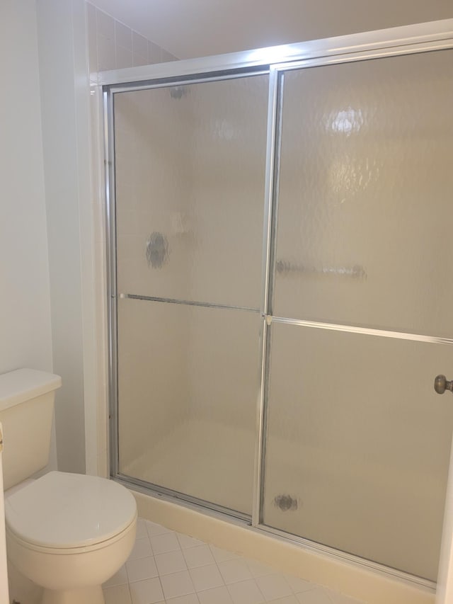 bathroom with walk in shower, toilet, and tile patterned flooring