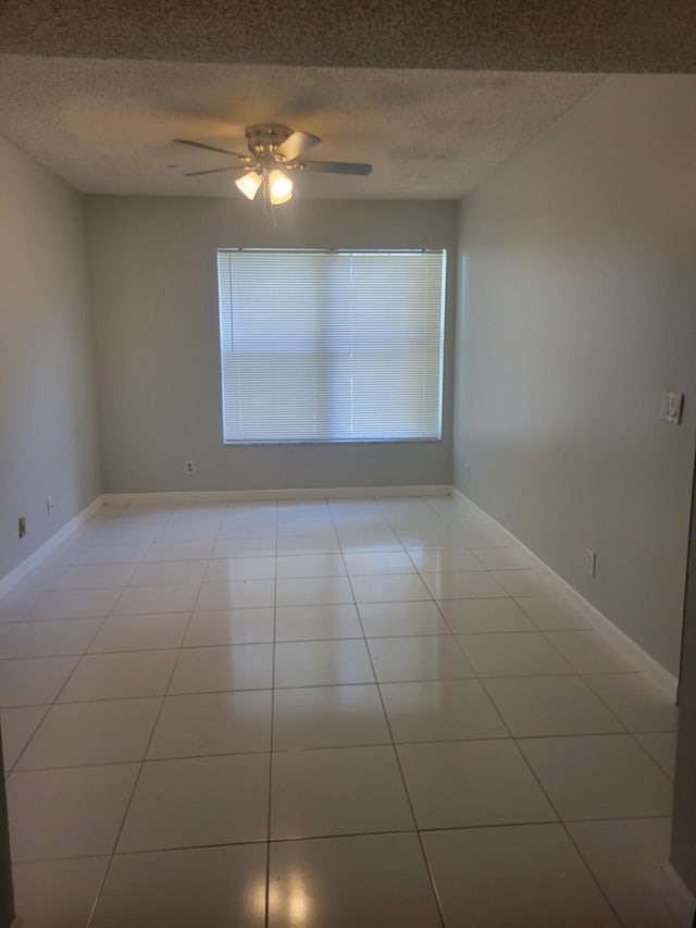 empty room featuring light tile patterned floors, a textured ceiling, and ceiling fan