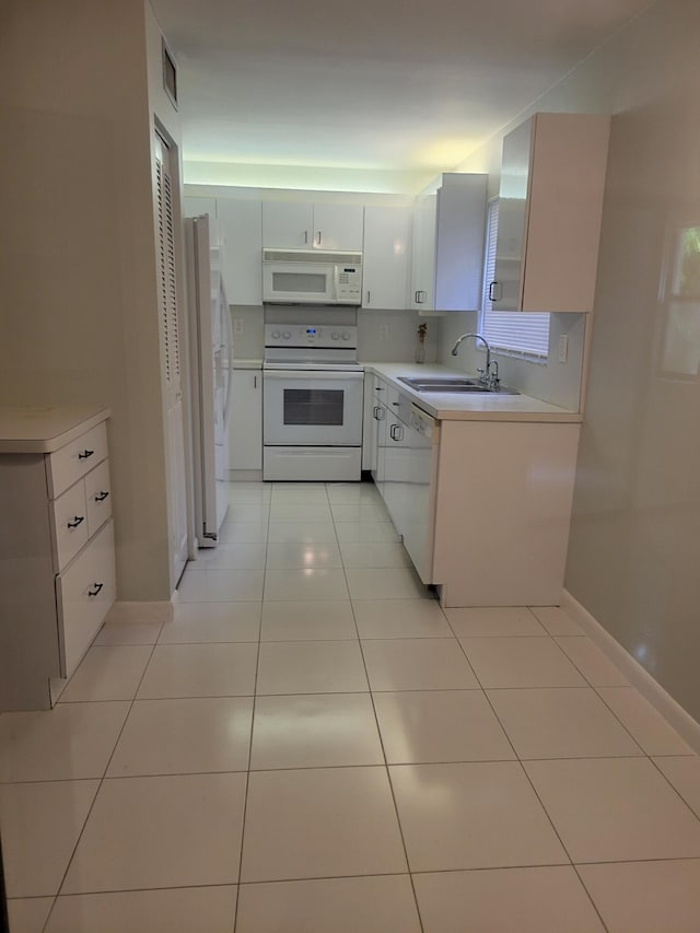 kitchen featuring white cabinetry, sink, light tile patterned floors, and white appliances