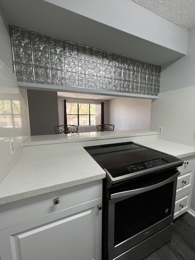 kitchen with electric stove, white cabinetry, dark hardwood / wood-style flooring, and light stone countertops