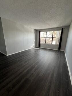 spare room featuring a textured ceiling and dark hardwood / wood-style flooring