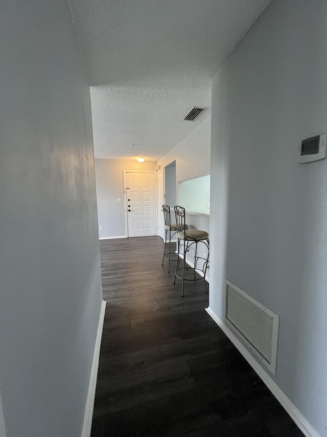 hall with dark hardwood / wood-style floors and a textured ceiling