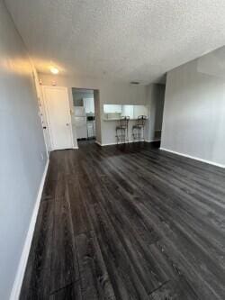 unfurnished living room with dark wood-type flooring and a textured ceiling