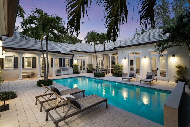 pool at dusk with a patio and french doors