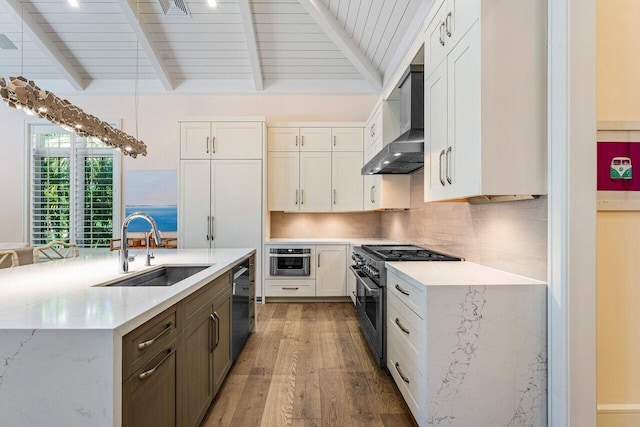 kitchen with appliances with stainless steel finishes, tasteful backsplash, white cabinetry, sink, and wall chimney range hood