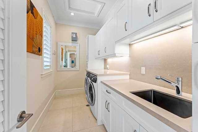 laundry area with light tile patterned flooring, sink, cabinets, separate washer and dryer, and ornamental molding