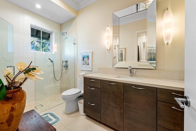 bathroom featuring tile patterned floors, toilet, vanity, and a tile shower