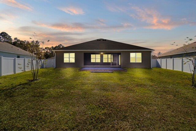 back house at dusk with a yard