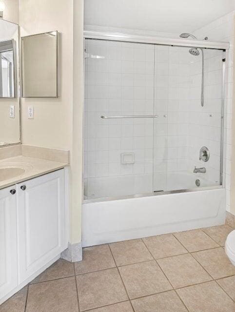 full bathroom with toilet, tile patterned floors, bath / shower combo with glass door, and vanity