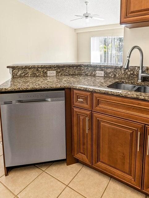 kitchen featuring dishwasher, sink, dark stone counters, ceiling fan, and a textured ceiling