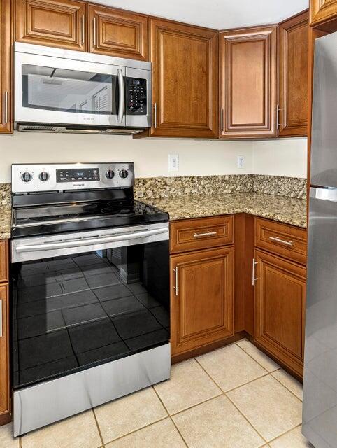 kitchen featuring light stone counters, appliances with stainless steel finishes, and light tile patterned floors