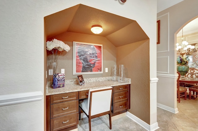 office area with an inviting chandelier, built in desk, and vaulted ceiling