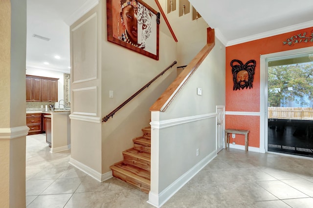 staircase featuring tile patterned floors, ornamental molding, and sink