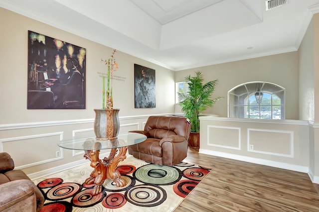 sitting room with ornamental molding, a tray ceiling, and hardwood / wood-style floors