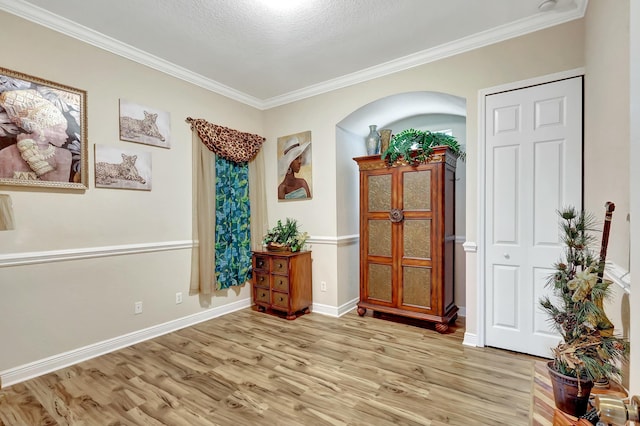 entryway with ornamental molding, a textured ceiling, and light hardwood / wood-style floors