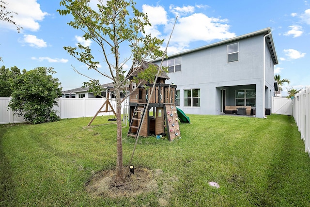 rear view of property with a yard, an outdoor hangout area, and a playground