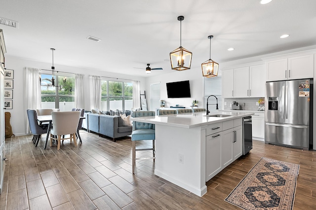 kitchen featuring sink, an island with sink, white cabinets, and stainless steel refrigerator with ice dispenser