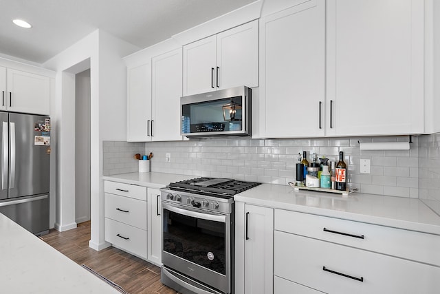 kitchen with decorative backsplash, dark wood-type flooring, white cabinets, and appliances with stainless steel finishes