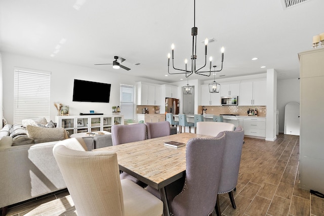 dining space featuring ceiling fan with notable chandelier