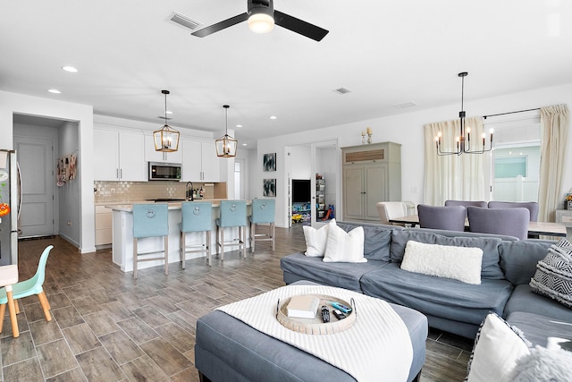 living room with ceiling fan with notable chandelier